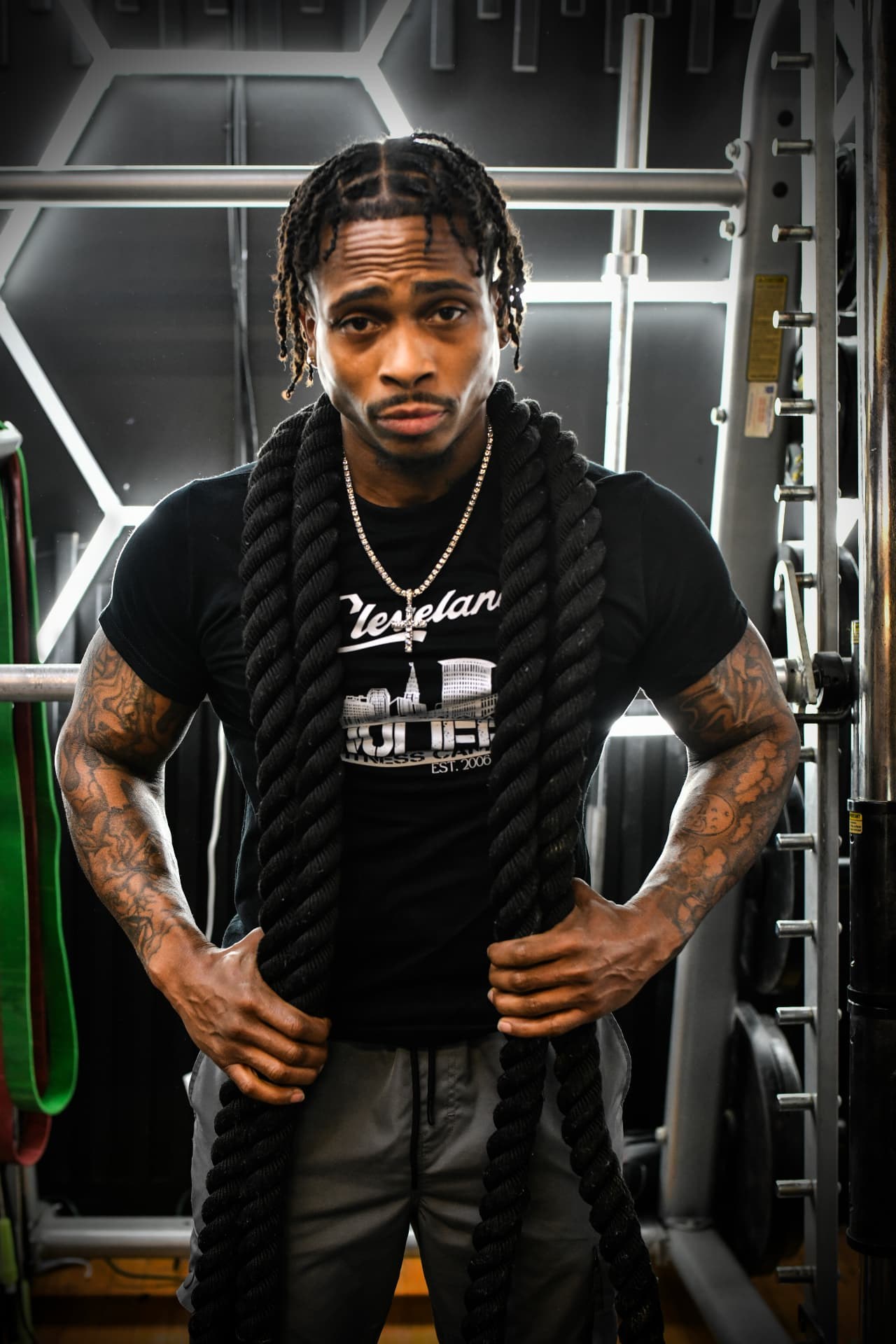 NuLife trainer with long locs posing in front of the studio's strength equipment