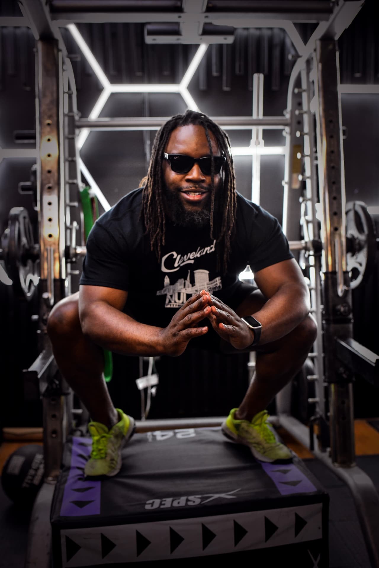 NuLife trainer wearing sunglasses and leaning on a stack of workout platforms